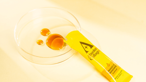 Liquid collagen supplement sachet in a glass bowl, resembling a petri dish.